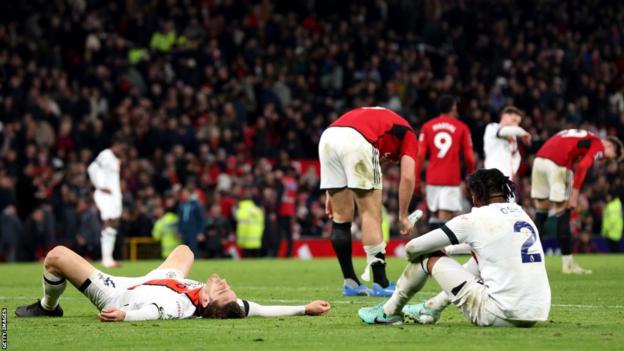 Luton players slumped on the ground after defeat at Manchester United