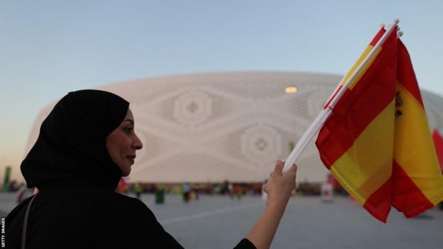 Une femme tenant un drapeau à l'extérieur d'un site de Coupe du monde