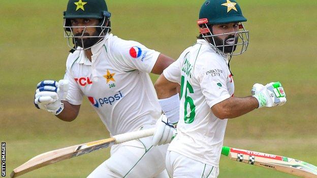 Los bateadores pakistaníes Abdullah Shafique (izquierda) y Mohammad Rizwan (derecha) corren entre los es counters