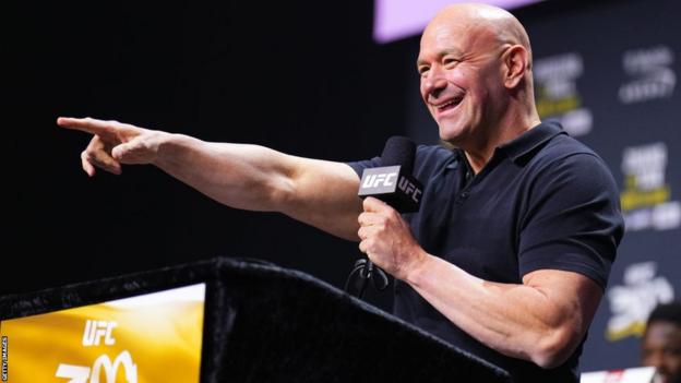 Dana White points as he speaks on the microphone at a news conference