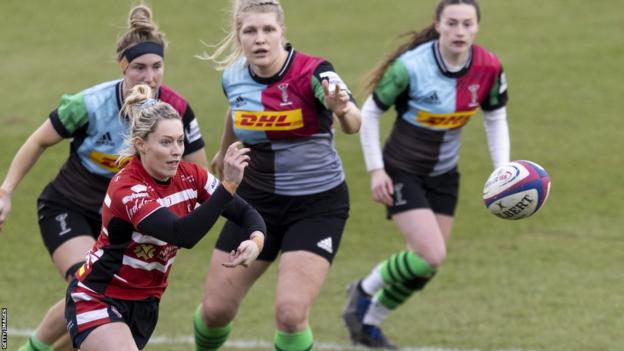 Natasha Hunt throws a rugby ball as Harlequins players run to defend