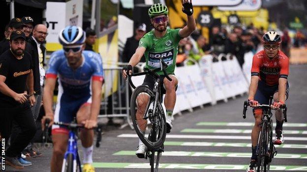 Peter Sagan (in green) pulling a wheelie across the finish line on stage 20