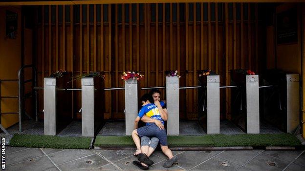 Une mère et son fils pleurent Maradona devant La Bombonera