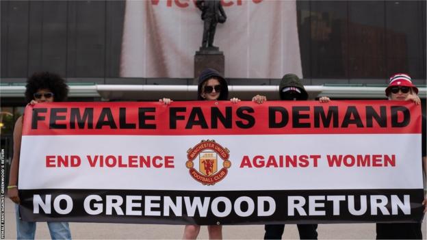 The group Female Fans Against Greenwood's Return holds up a banner in front of Old Trafford