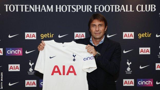 Antonio Conte holds up a Tottenham shirt