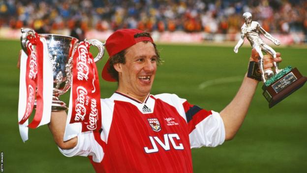 Paul Merson holds trophies while at Arsenal