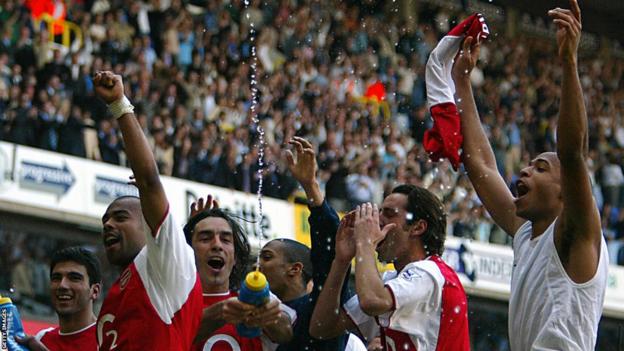 Arsenal players celebrate with their arms aloft and throwing their arms in the air after winning the league.