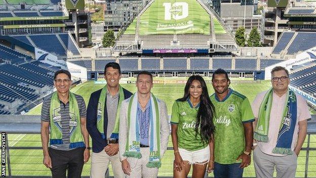 Adrian Hanauer (far left) and Drew Carey (far right) with the new Ownership Group additions, led by (L to R) Terry Myerson, Macklemore, Ciara and Russell Wilson