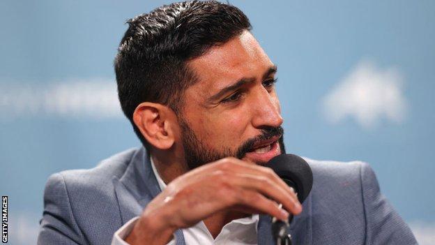 Amir Khan speaks on the microphone at a press conference