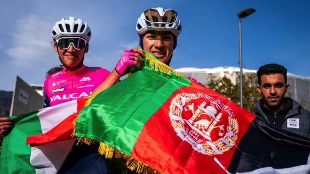 Two cyclists holding flags after their win