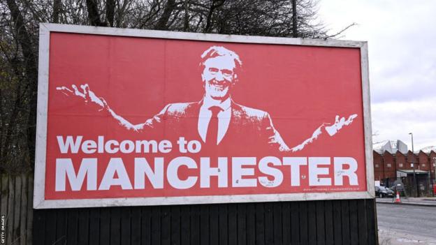 A billboard near Old Trafford shows a picture of Sir Jim Ratcliffe above the words 'Welcome To Manchester'