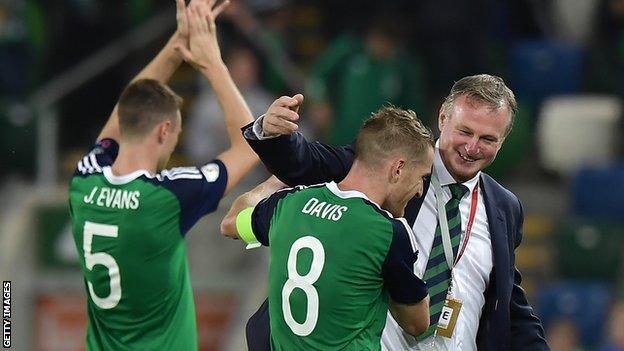 Michael O'Neill celebrates with Northern Ireland players Jonny Evans and Steven Davis