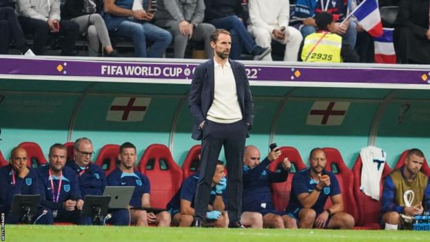 Gareth Southgate standing in front of the England dugout during England's World Cup quarter-final against France