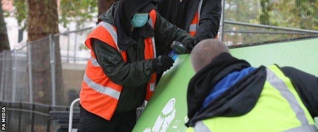 Workers assemble screens to keep spectators from viewing the race