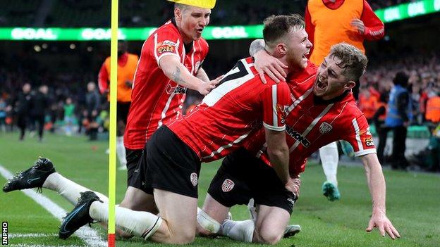 Jamie McGonigle (right) and Shane McEleney (left) celebrate with Derry's two-goal hero Cameron McJannet