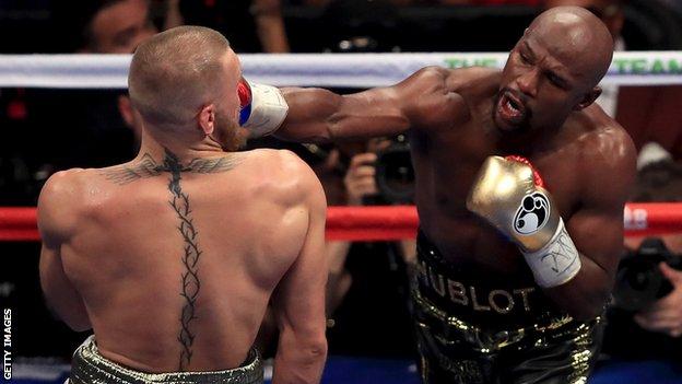 Floyd Mayweather throws a punch at Conor McGregor during their super welterweight boxing match in August 2017