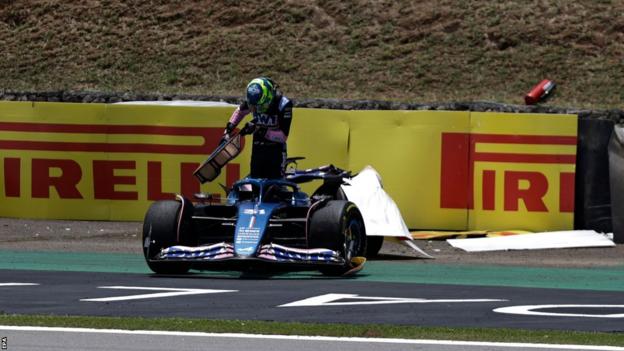 Esteban Ocon climbs out of his Alpine after he crashed into the barrier following a collision with Aston Martin's Fernando Alonso