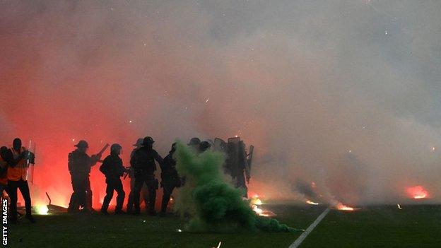 Riot police officers clash with Saint-Etienne's fans who invaded the pitch after being defeated by Auxerre