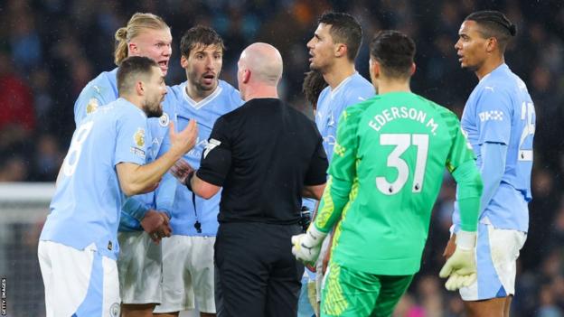 Man City players surround the referee at the final whistle
