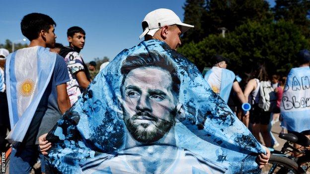 Argentina fans wears a Lionel Messi flag draped over his shoulders
