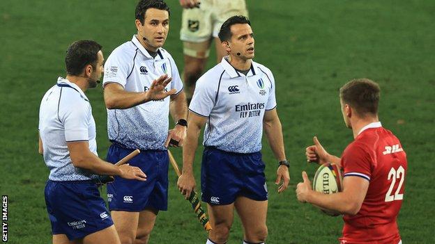 Three referees talk with Owen Farrell