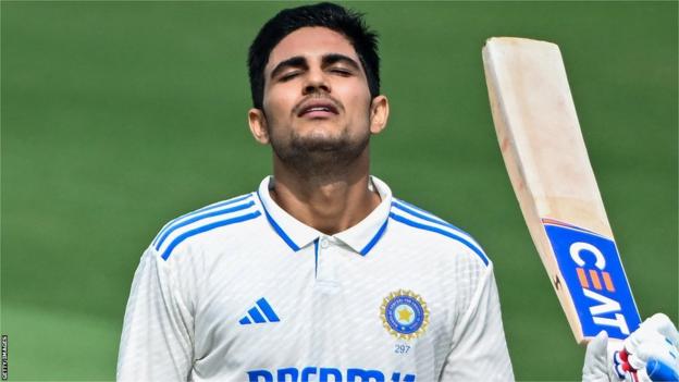 India batter Shubman Gill raises his bat in celebration after hitting a century