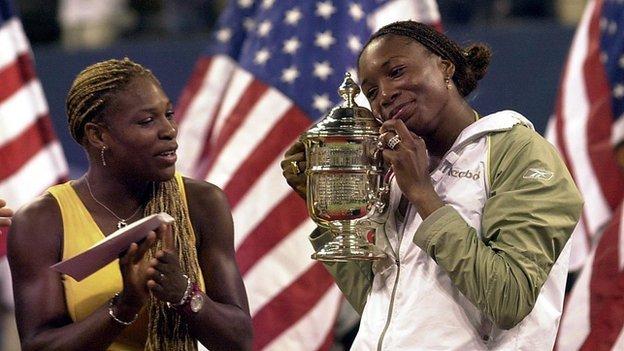 Serena Williams applauds her sister Venus who holds the 2001 US Open trophy