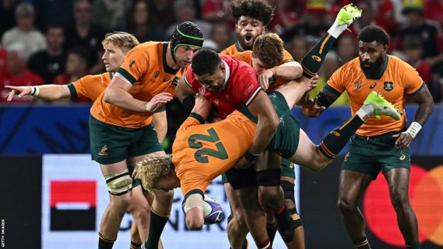 Australia's fly-half Carter Gordon is tackled by Wales' number eight Taulupe Faletau