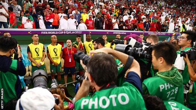 Cristiano Ronaldo and the Portugal substitutes are surrounded by photographers prior to kick-off