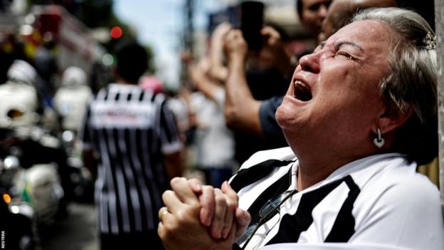 An emotional Pele fan cries as his body is carried through the streets of Santos