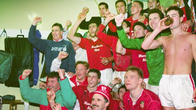 Wrexham players and staff celebrate in the dressing room after victory over Arsenal