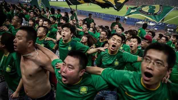 Beijing Guoan fans sing and jump with their backs to the pitch during a Chinese Super League game