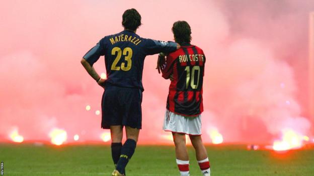 Marco Materazzi leans on Rui Costa's shoulder as the pair watch smoke rise from flares thrown from the stands during the 2005 Champions League quarter-final between AC Milan and Inter Milan