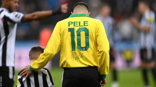 Newcastle midfielder Bruno Guimaraes walks onto the pitch, while wearing a signed Pele 10 shirt, prior to the match against Leeds