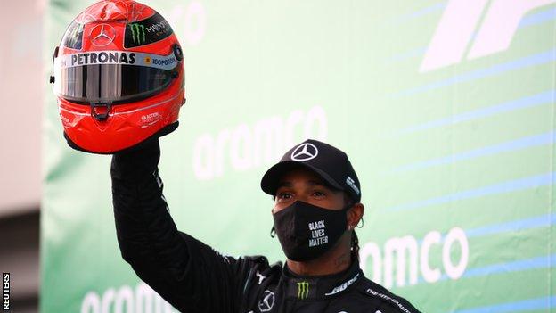 Lewis Hamilton holds up Michael Schumacher's race helmet