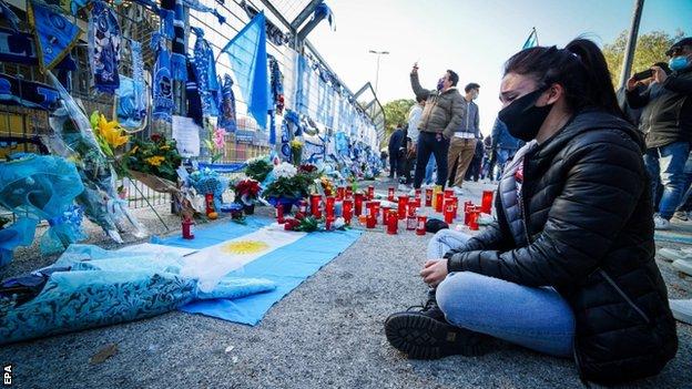 A visibly upset woman sat looking at tributes to Diego Maradona outside the San Paolo stadium