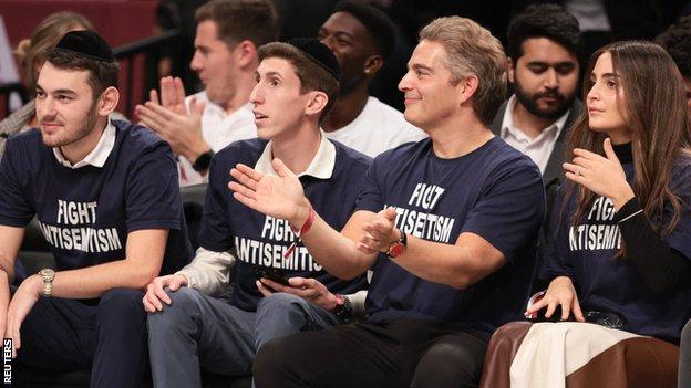 Fans at Brooklyn Nets game wear 'Fight Anti-Semitism' T-shirts.