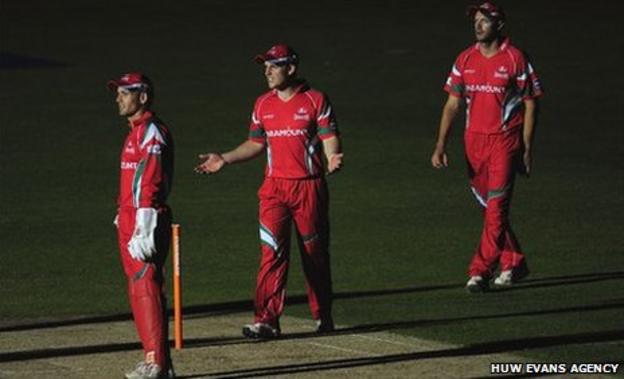 Glamorgan players wait in the dark for play to restart