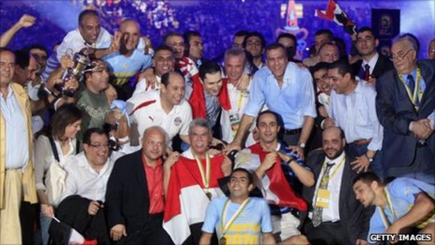 The sons of Egyptian president Hosni Mubarak (half-right, standing and crouching) celebrate winning the Nations Cup in 2010 with the national team