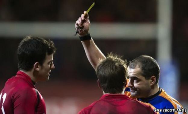 Edinburgh's Matt Scott is shown a yellow card by referee Peter Allan