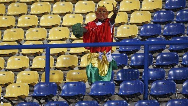 A Guinea fan stands among rows of empty seats