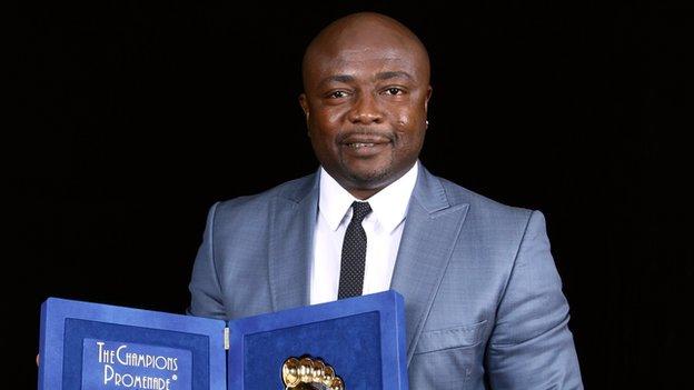 Abedi Pele holds an award he was given in 2011