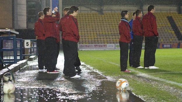 Players stand in the puddles at Almondvale before the postonement