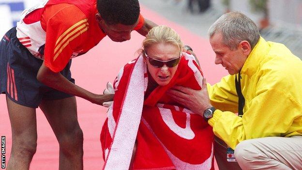 Haile Gebrselassie (L) and chief organiser Wolfgang Konrad (R) help Paula Radcliffe