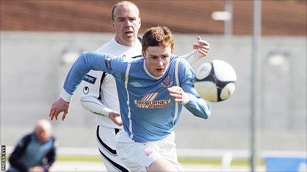 David Larmour of Lisburn Distilelry watches as Aaron Stewart of Ballymena comes away with the ball