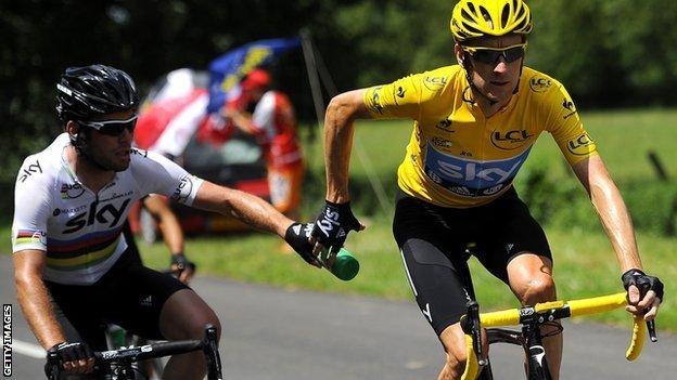 Mark Cavendish feeds Bradley Wiggins a water bottle