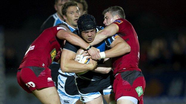 Tom Ryder (centre) is halted by Scarlets' Scott Williams and Tavis Knoyle (right)