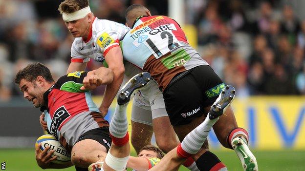 Harlequins number eight Nick Easter is brought to ground as Saracens fly-half Owen Farrell gets involved
