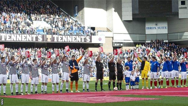 Queen's Park and Rangers players prepare for kick-off in front of a large crowd at Ibrox