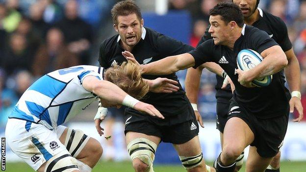 All Blacks fly-half Dan Carter hands off Scotland back rower David Denton